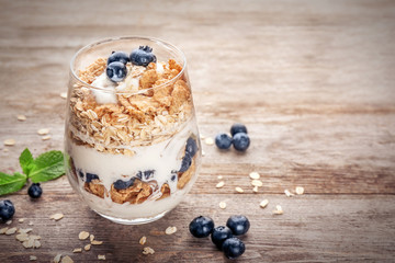 Glass with oat flakes and fresh berries on wooden background