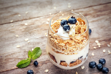 Glass with oat flakes and fresh berries on wooden background