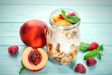 Jar with oat flakes and fresh peaches on wooden background