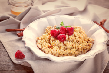 Plate with oatmeal and raspberries on table