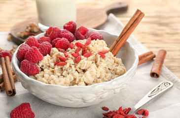 Bowl with oatmeal, raspberries and goji on table
