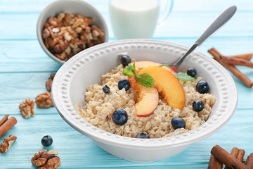 Bowl with oatmeal, peaches and berries on table