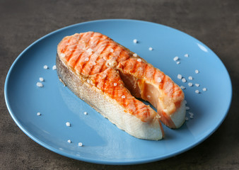 Plate with delicious salmon steak on table