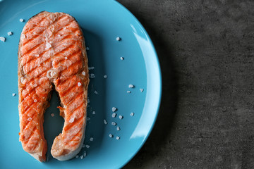 Plate with delicious salmon steak on table