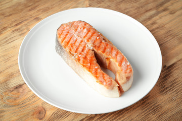Plate with delicious salmon steak on table
