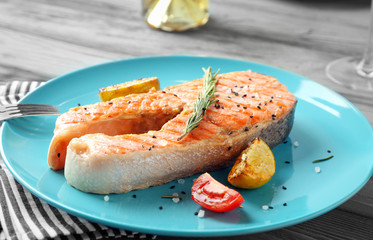 Plate with delicious salmon steak on table