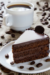 Cup of coffee, coffee beans on table with sackcloth, piece of chocolate cake, closeup