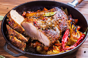 Roasted meat with spices in pan on dark rustic background, close up. 