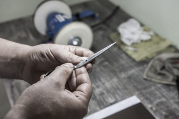 master man looks at the scissors and going to sharpen them