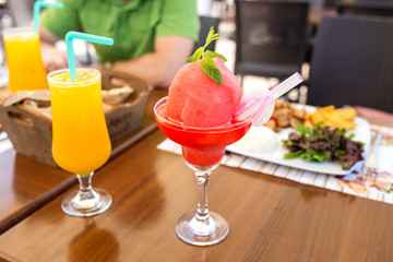 the man is having breakfast in a cafe or restaurant with orange and watermelon juice and smoothies on the table