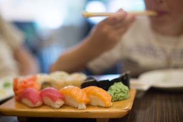 Obraz na płótnie Canvas Boy eating sushi with chopsticks.