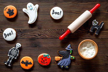 Cook halloween gingerbread cookies in shape of skeleton, mummy. Sweets near desk and rolling pin. wooden background top view copyspace