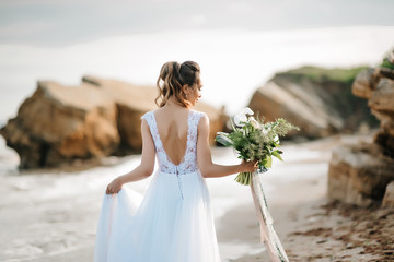 Fototapeta na wymiar bride with a wedding bouquet on the shore sea
