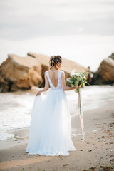 Fototapeta na wymiar bride with a wedding bouquet on the shore sea