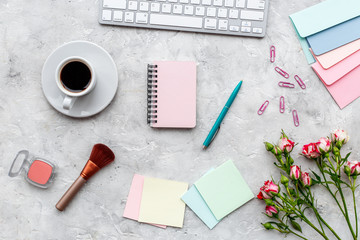 female work space with flowers, coffee, cosmetics and notebook stone background top view mockup