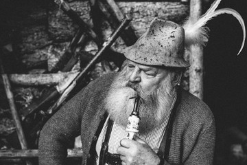 black and white portrait of a typical old austrian bearded man with millinery smoking a pipe