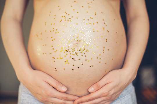 Close up of pregnant woman's belly covered with glitter