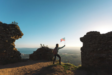 Rear view of woman holding American flag while standing on mountain