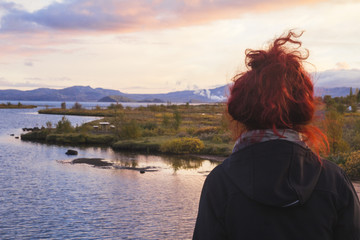 Girl with red head  watching river and mountains