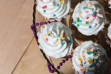 Cakes with white cream and colored powder on a glass stand