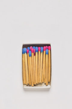 Red and blue wooden matches in a match box on white