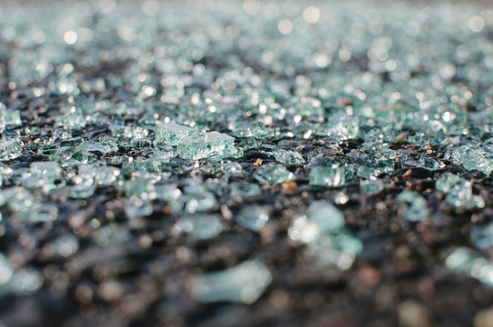 Close-up of shattered windshield glass on pavement