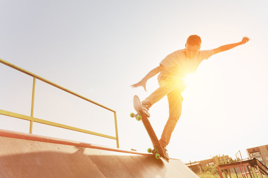 Teen skater hang up over a ramp on a skateboard in a skate park