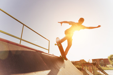 Fototapeta na wymiar Teen skater hang up over a ramp on a skateboard in a skate park