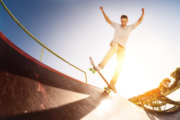 Fototapeta na wymiar Teen skater hang up over a ramp on a skateboard in a skate park
