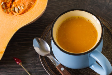 Pumpkin soup with cream and parsley on dark wooden background