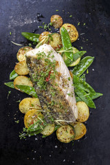 Fried cod fish fillet with vegetable and potatoes as top-view on old board