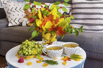 Autumn fall leaves bouquet,cups of tee and grapes .Morning time.Still life concept.