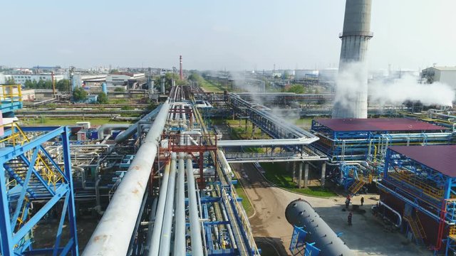 Drone Moves over Pipelines at Gas and Oil Plant against Wide Sky