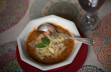 Rustic old world tomato soup with crusty bread and fresh basil in ironstone bowl with silver vintage spoon