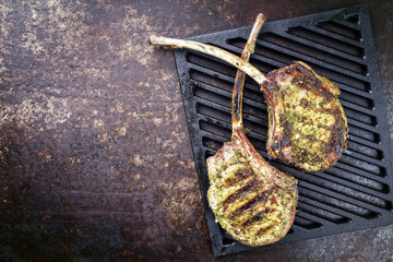 Barbecue tomahawk pork steak as top view on a griddle with copy space on left