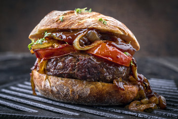 Barbecue wagyu cheeseburger with onions and tomatoes as close-up on a grillage