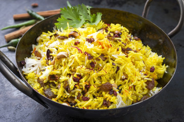 Indian vegetarian biryani with nuts and raisins as close-up in a korai