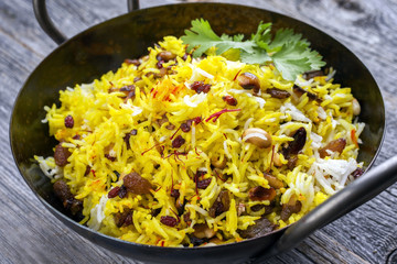 Indian vegetarian biryani with nuts and raisins as close-up in a korai