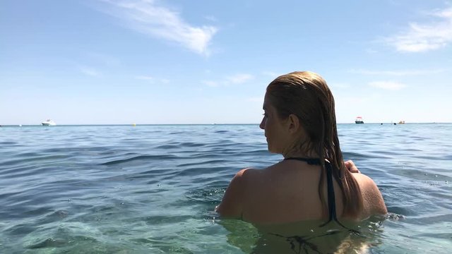 Blonde female plays in crystal clear sea water slow-mo footage - Caucasian woman on French coast slow motion