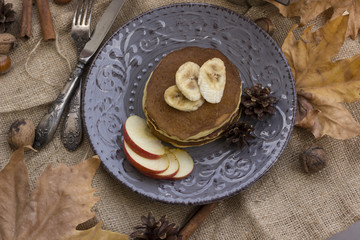 A composition of nuts, pancakes, bananas and apple on a nice autumn themed background