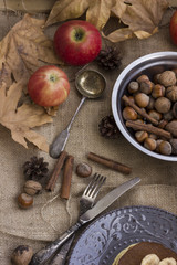 A composition of nuts, pancakes, bananas and apple on a nice autumn themed background