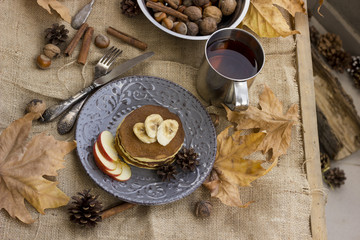A composition of nuts, pancakes, bananas and apple on a nice autumn themed background