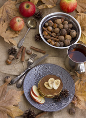 A composition of nuts, pancakes, bananas and apple on a nice autumn themed background