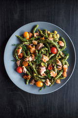 Salmon and spinach spaghetti served on dark wooden background .