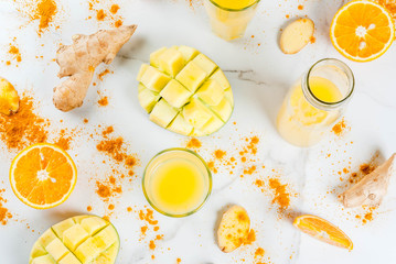 Indian cuisine recipes. Healthy food, detox water. Traditional Indian mango, orange, turmeric and ginger smoothie, on a white marble table. Copy space top view