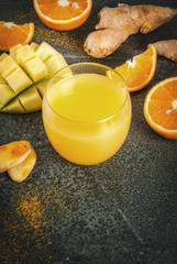 Indian cuisine recipes. Healthy food, detox water. Traditional Indian mango, orange, turmeric and ginger smoothie, on a dark stone table. Copy space