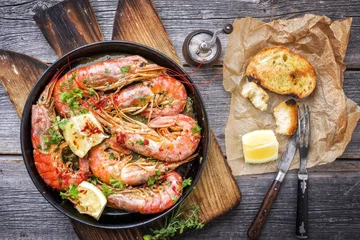 Fotobehang Traditional fried black tiger prawn with garlic bread as top view in a black frying pan © HLPhoto
