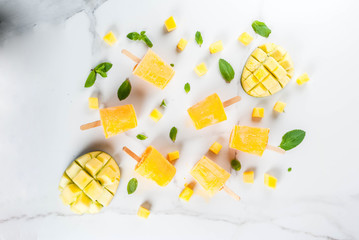 Ice cream, popsicles. Organic dietary foods, desserts. Frozen mango smoothie, with mint leaves and fresh mango fruit, on a white marble table. Copy space top view