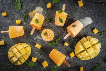 Ice cream, popsicles. Organic dietary foods, desserts. Frozen mango smoothie, with mint leaves and fresh mango fruit, on black stone table. Copy space  top view