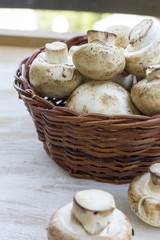 fresh mushrooms in a basket on the wooden table.